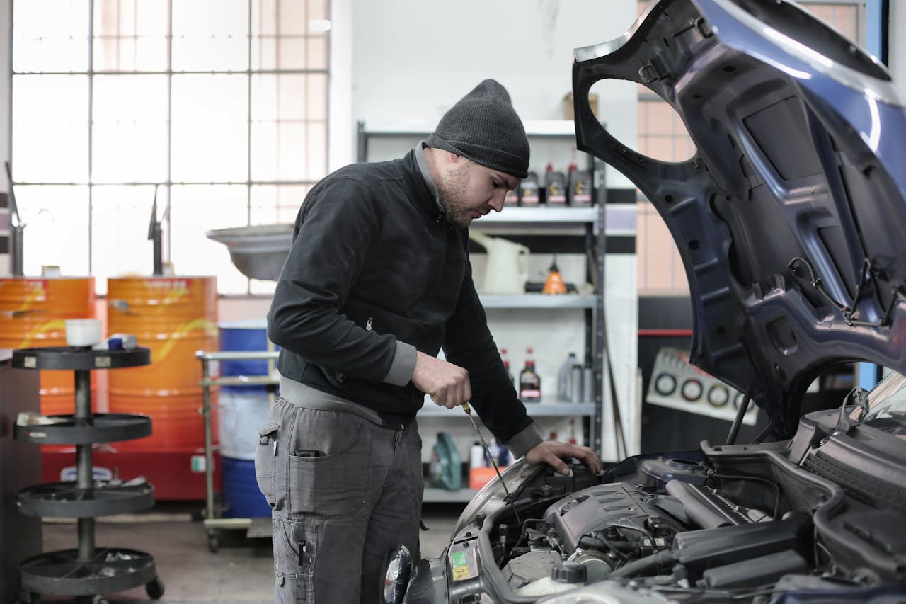 Kontakt Mechanic checking a car engine in a garage, ensuring quality maintenance and repair.